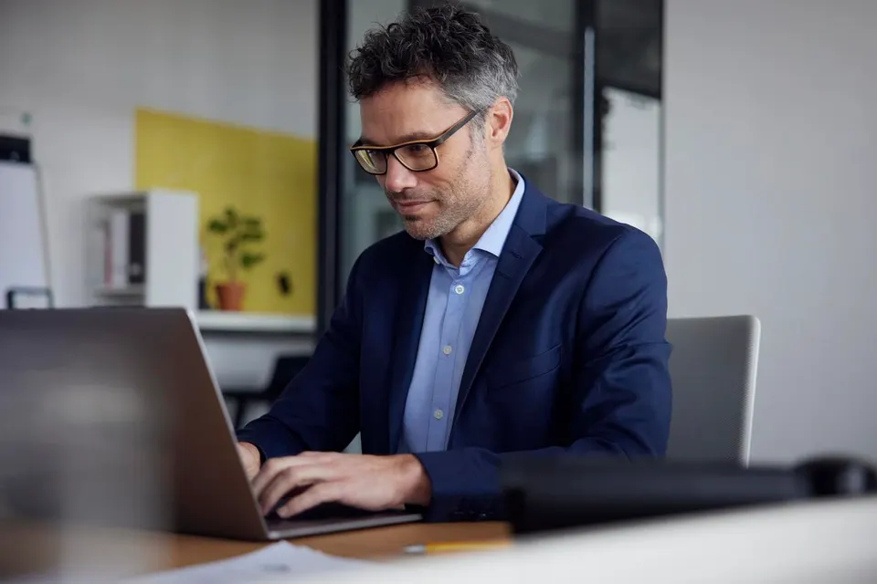 Businessman wearing eyeglasses using laptop at work place