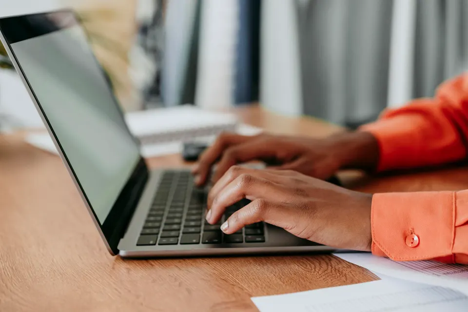 Hands of young businesswoman using laptop at desk