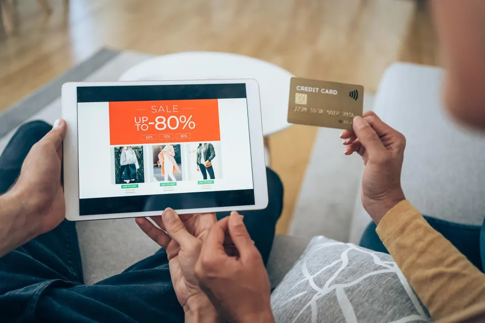 Lovely couple sitting on the sofa at home and using tablet for online shopping.