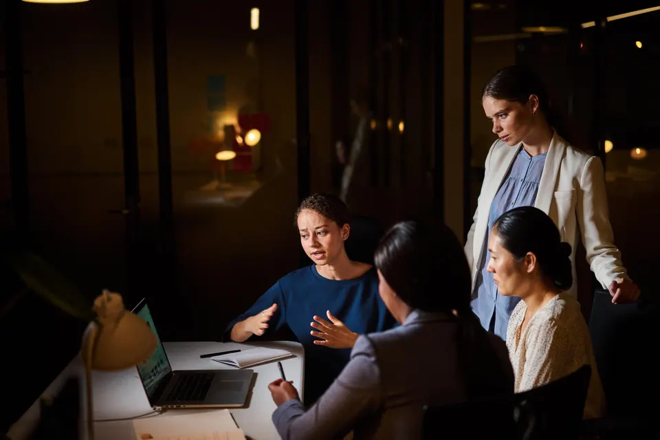 Diverse businesswomen working at an office desk at night