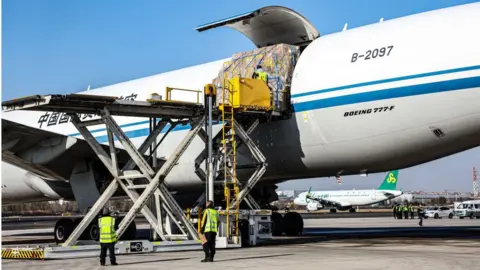 Getty Images Staff members load cargo onto an aircraft at a Chinese airport.