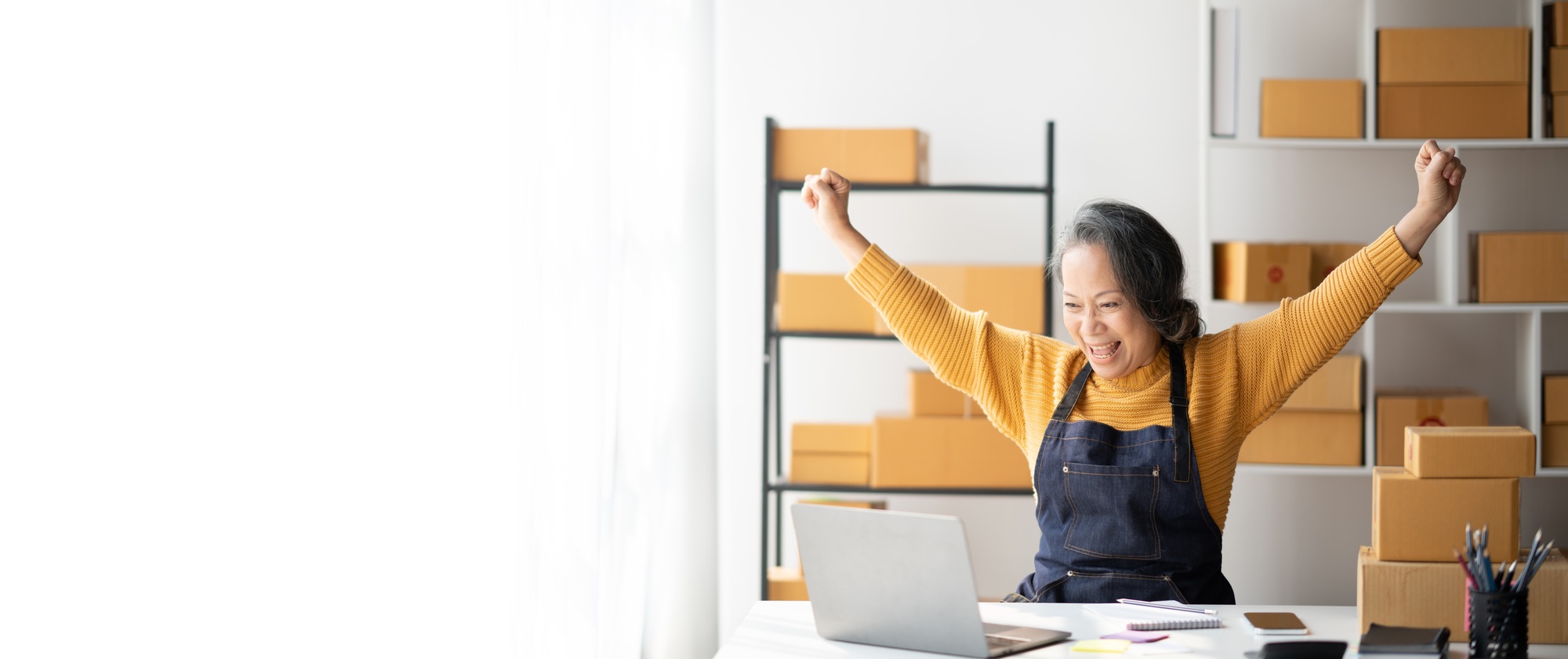 Happy successful small business owner celebrating her highest sales, raising her hands in the ai