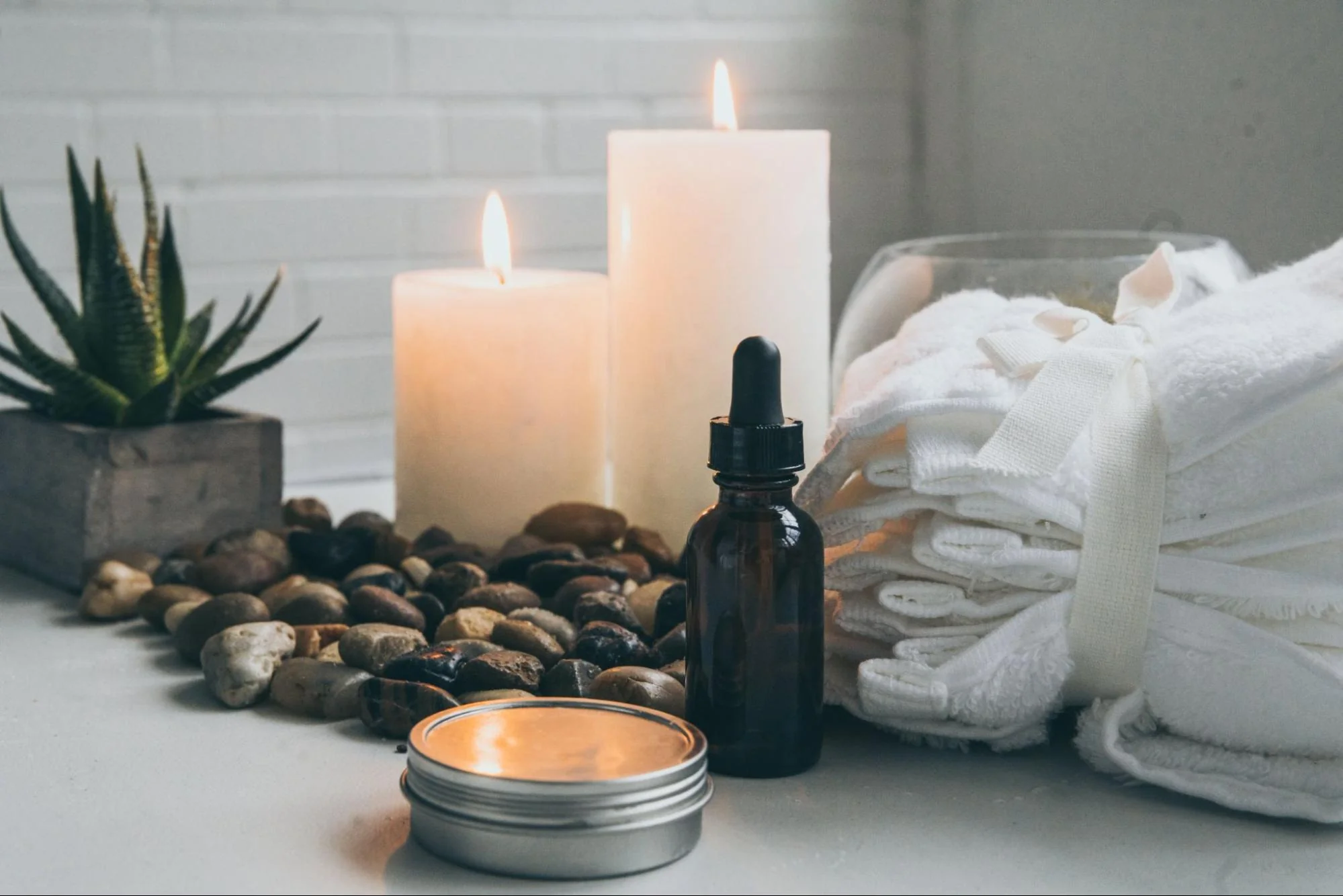 Lit candles, homemade natural products, and clean white towels in bathroom.