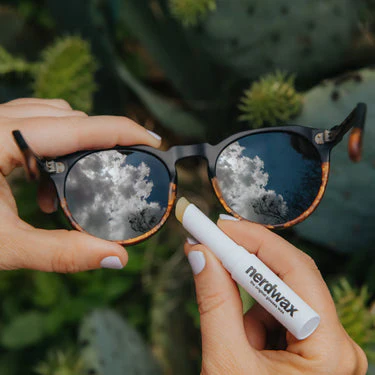 A person uses a nerdwax stick on their sunglasses