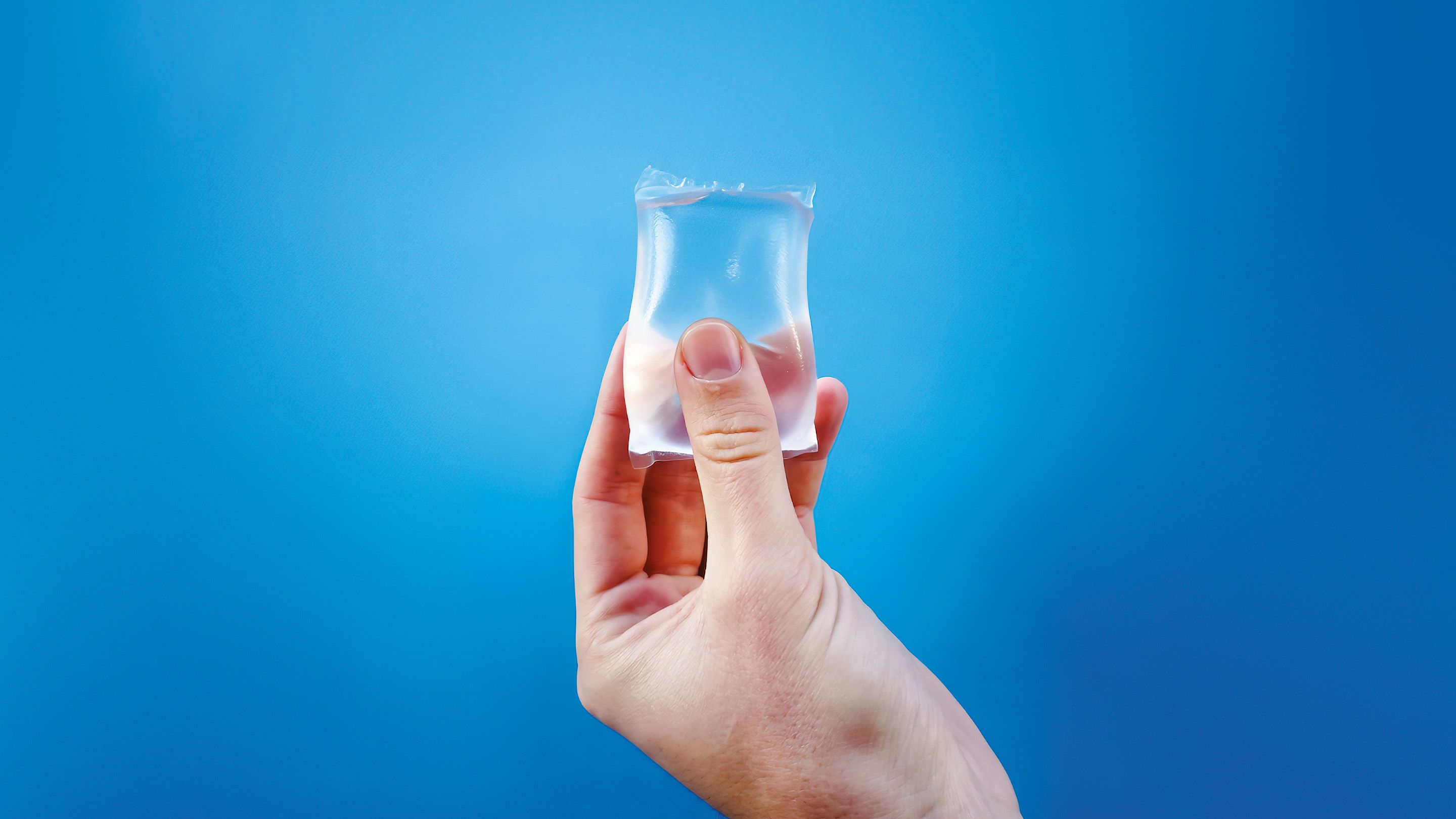 hand holding a transparent package of water