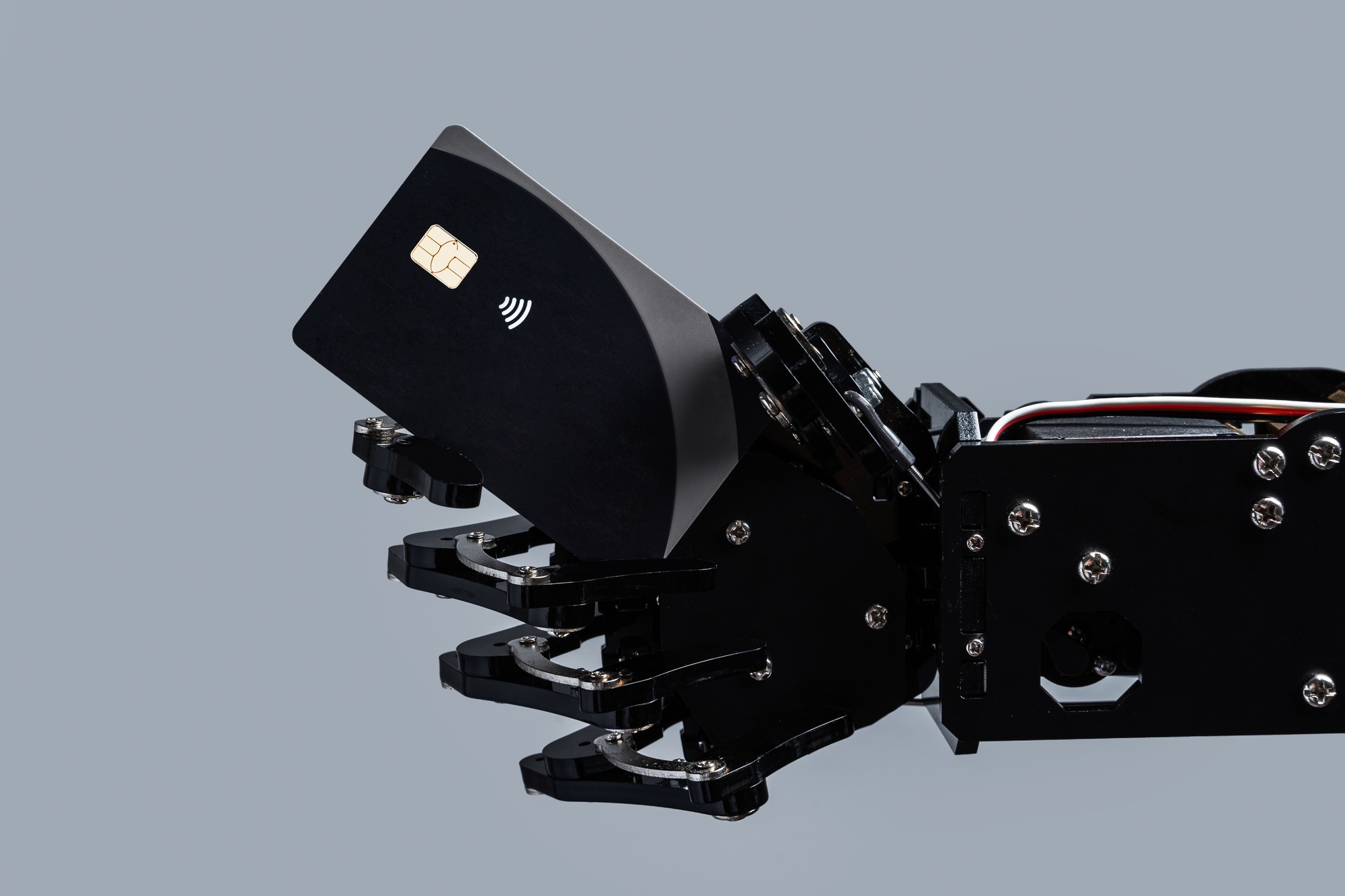 Real robotic hand with black contactless payment card.