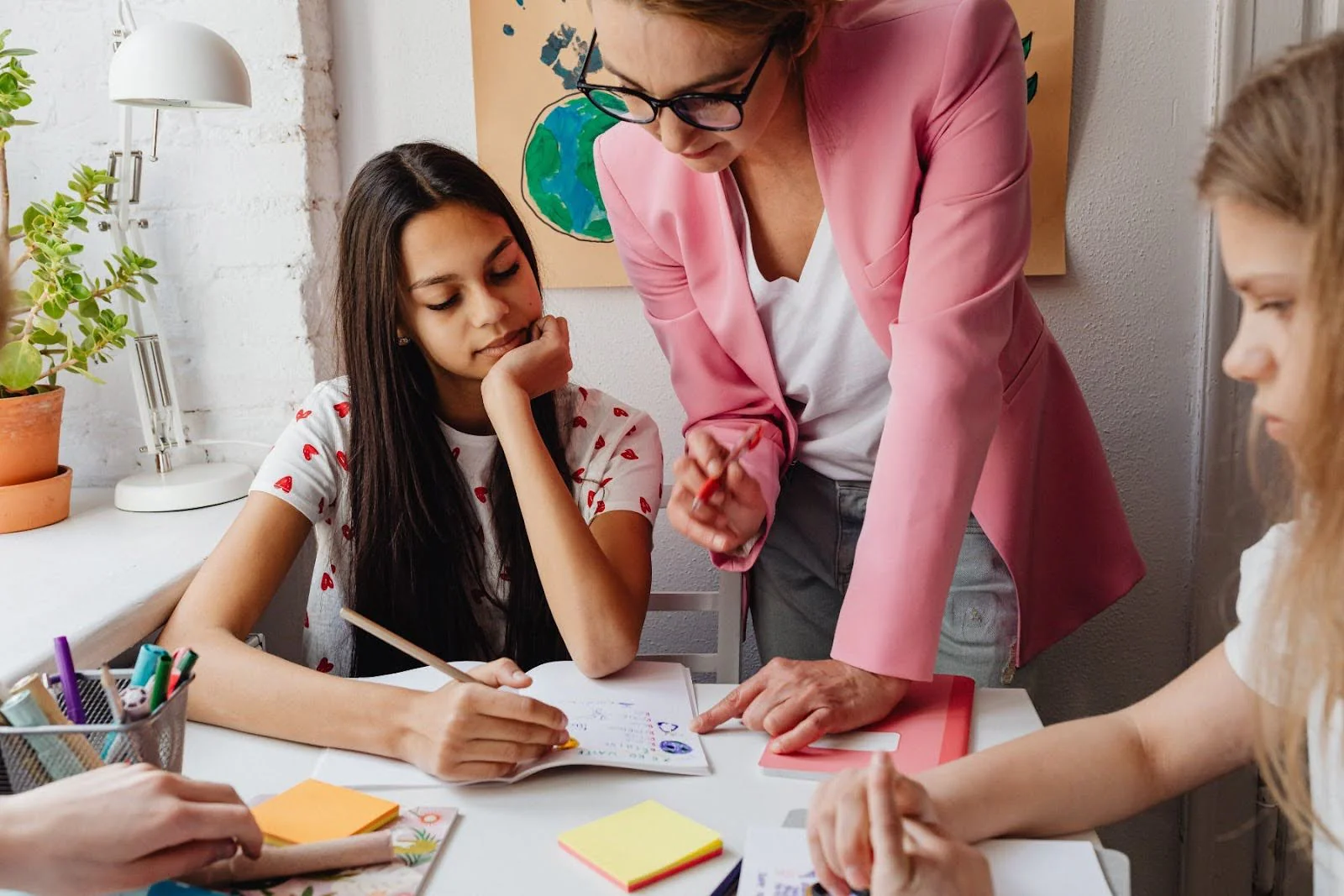 A group of children get help from an adult with some school work.