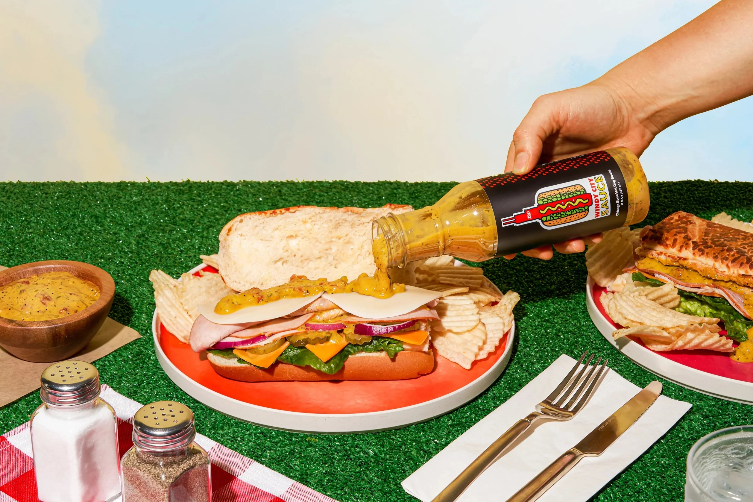 A person pours hot sauce on a hot dog