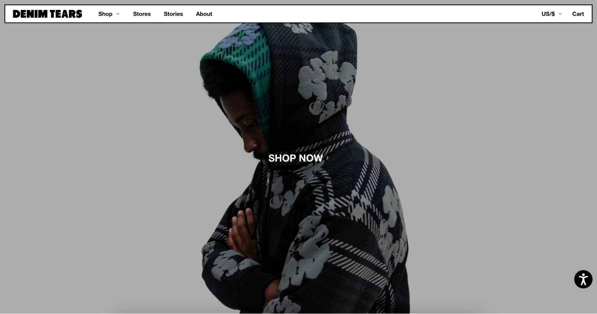 Denim Tears homepage featuring model in patterned hoodie with arms crossed and “Shop Now.”