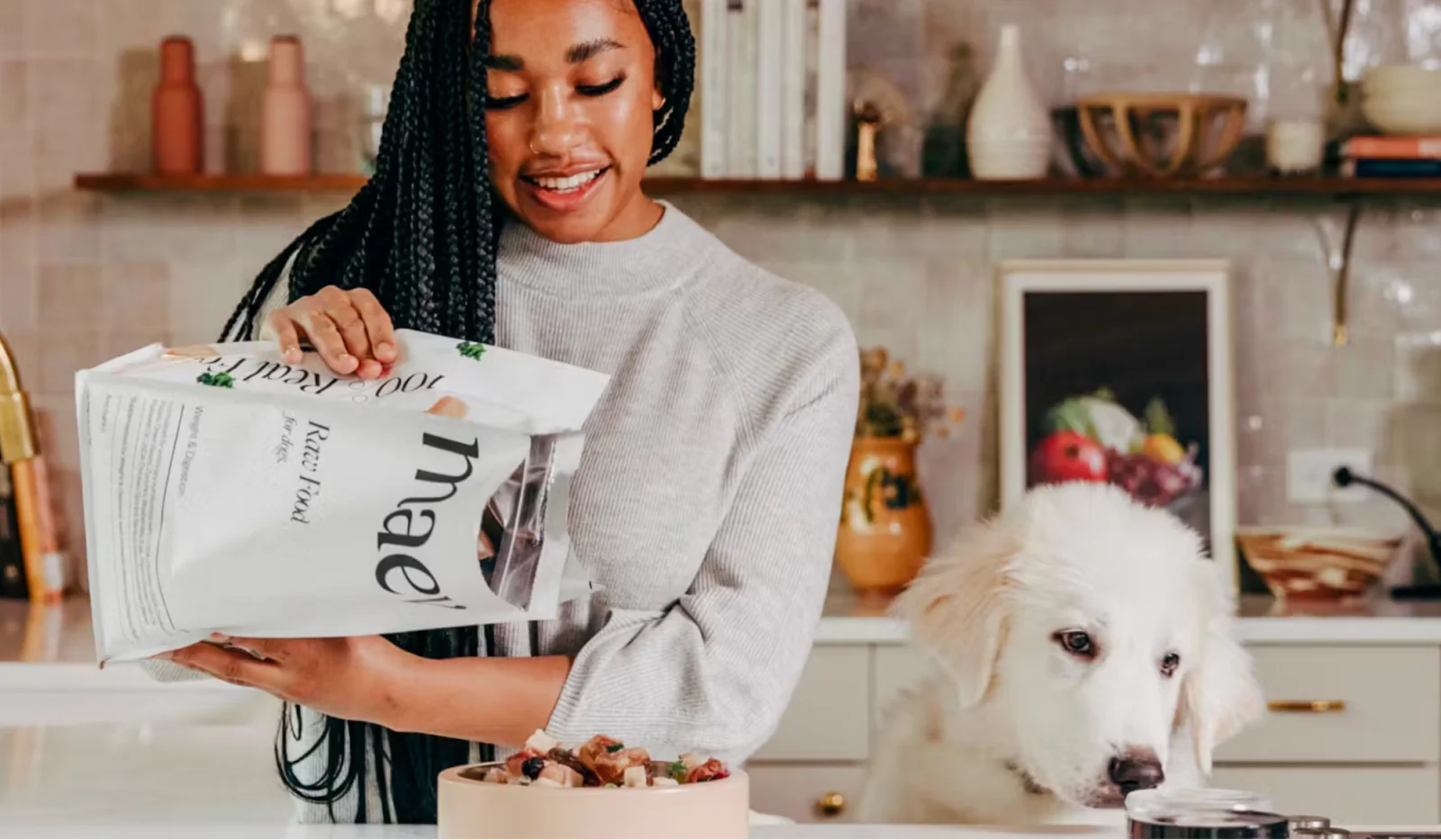 Photo of a dog owner pouring Maev organic, raw dog food into a bowl for her awaiting pup.