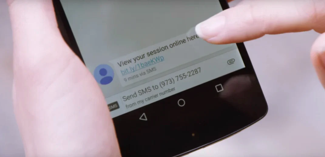 A customer checks a text sent from Rebecca Minkoff about a recent shopping appointment